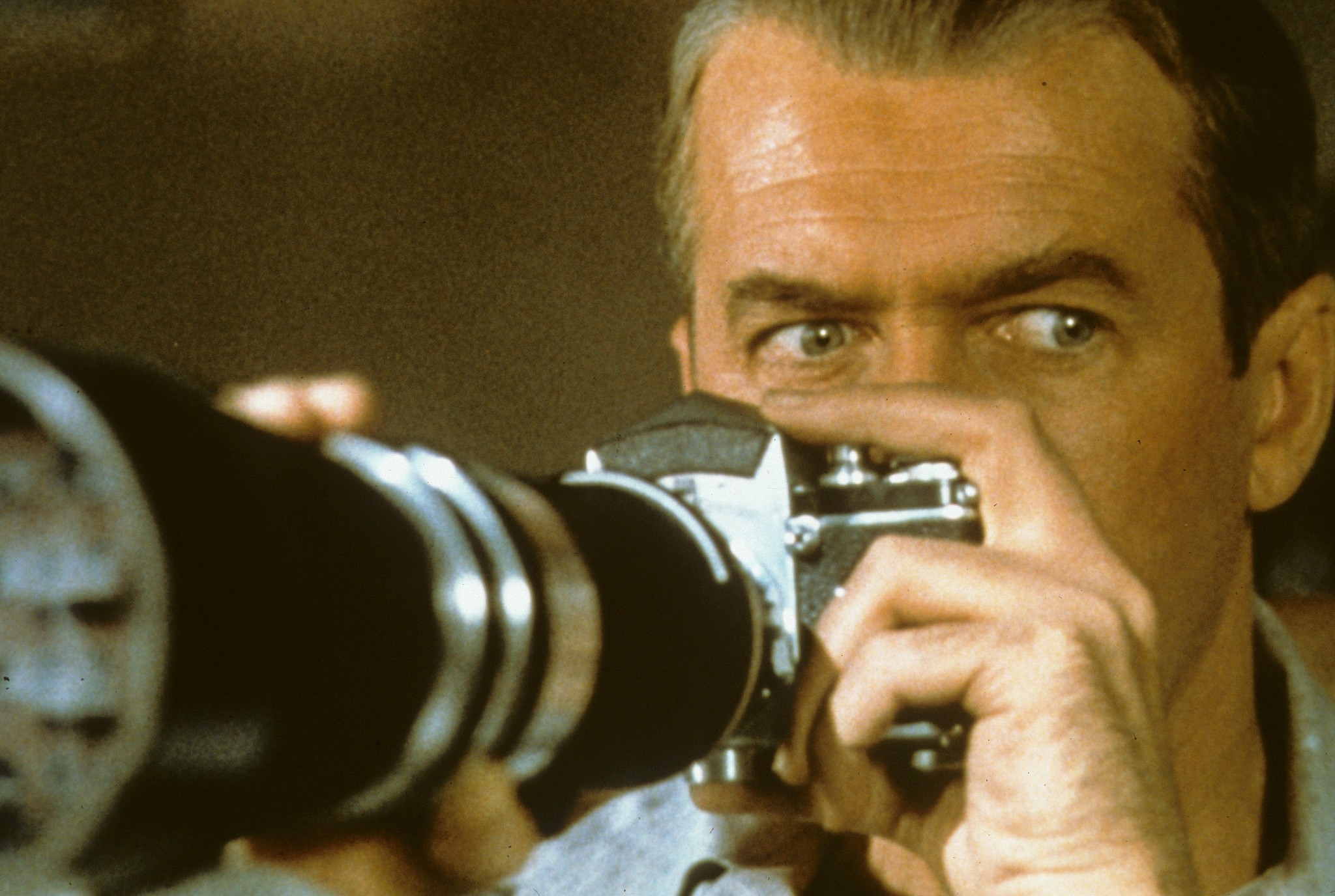 A man holds a camera in Rear Window.