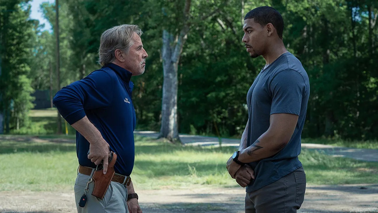 Don Johnson coloca a mão em uma arma enquanto Aaron Pierre fica à sua frente.