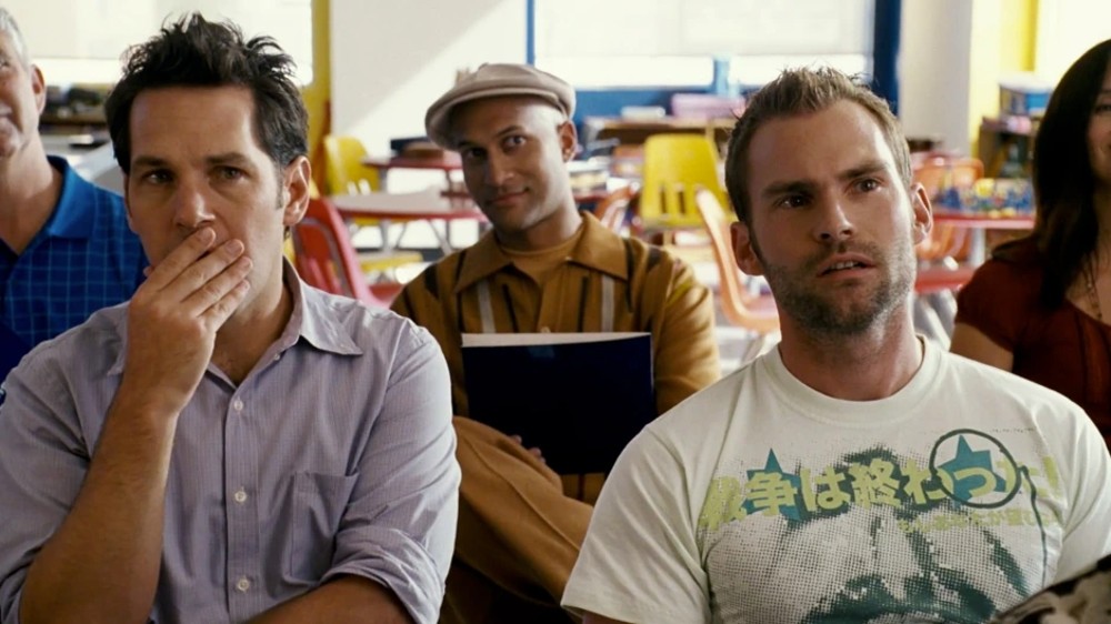 Two men sit in a classroom in Role Models.