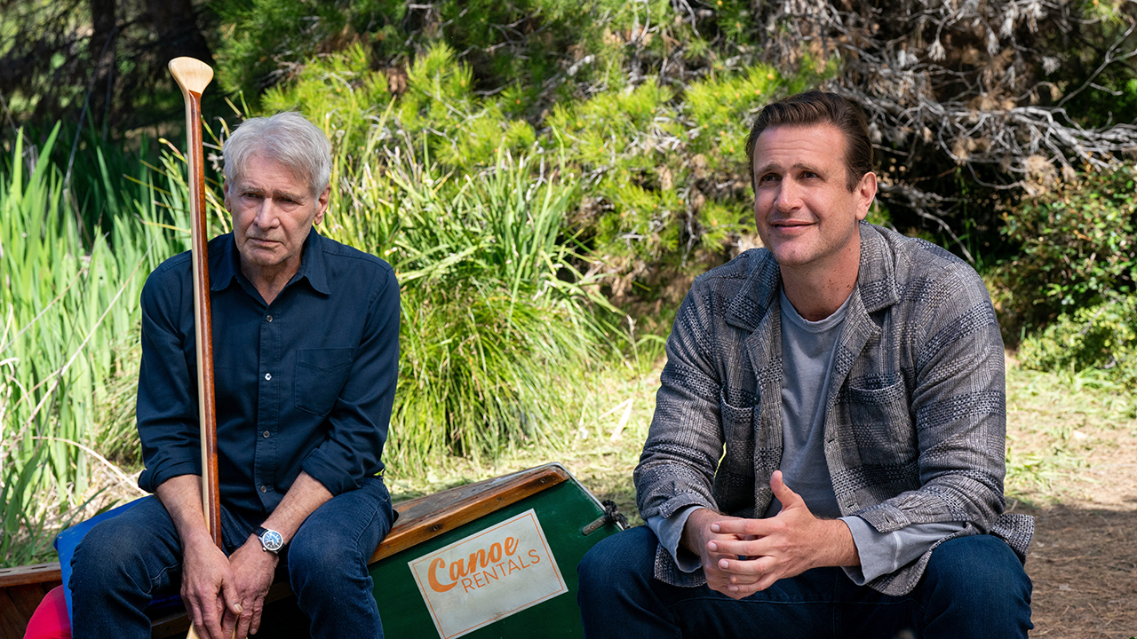 Harrison Ford and Jason Segel sitting side by side outside in a scene from Shrinking.