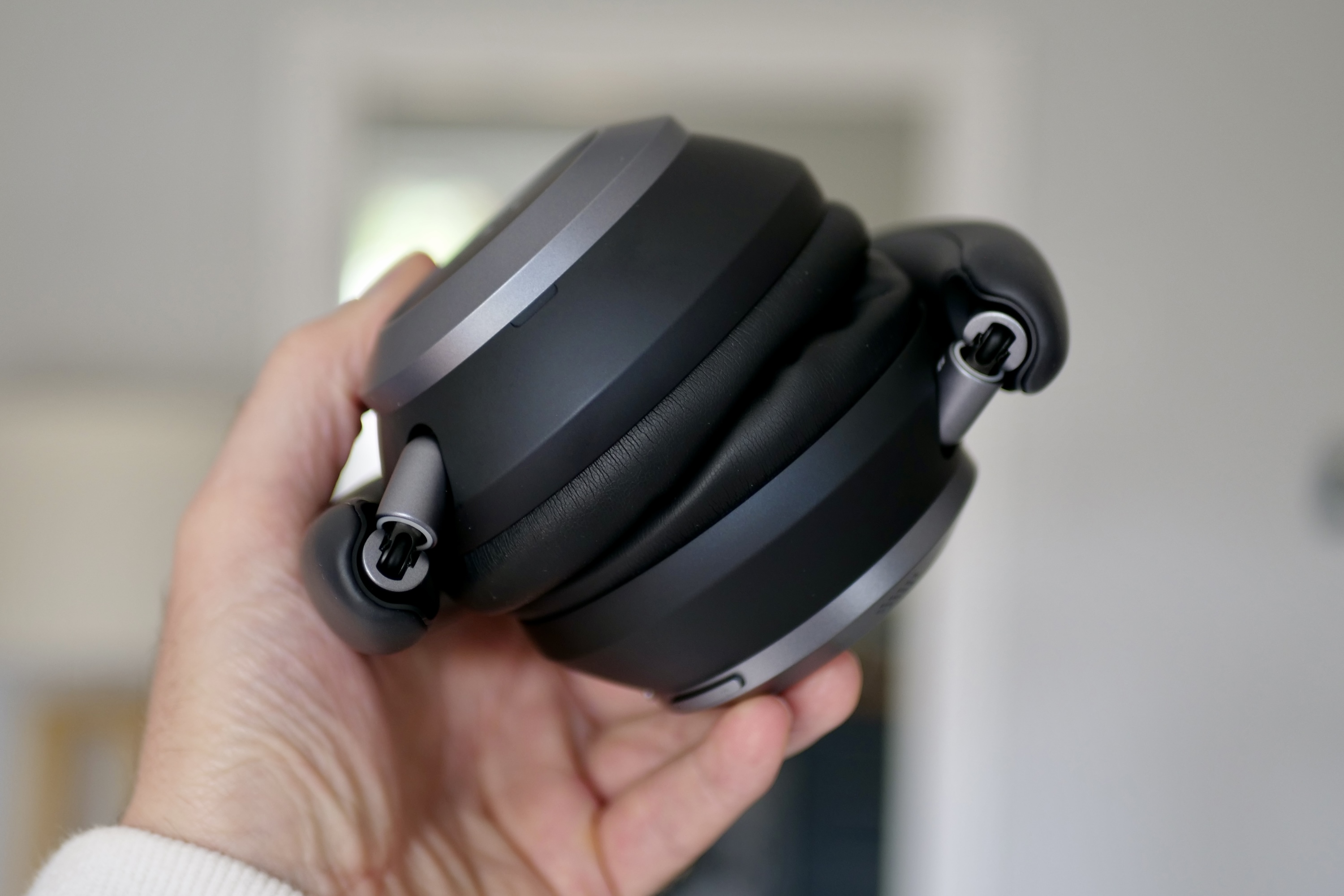 A person holding the folded Soundcore Space One Pro headphones.