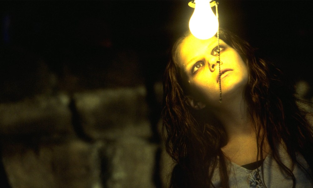 A ghost girl looks at a light bulb in Stir of Echoes.