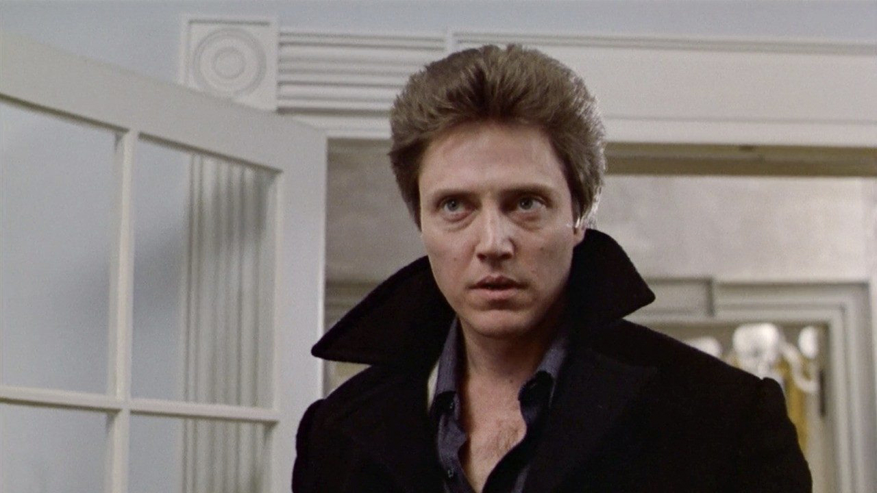 Christopher Walken standing in a home with a black jacket collar up staring in The Dead Zone.