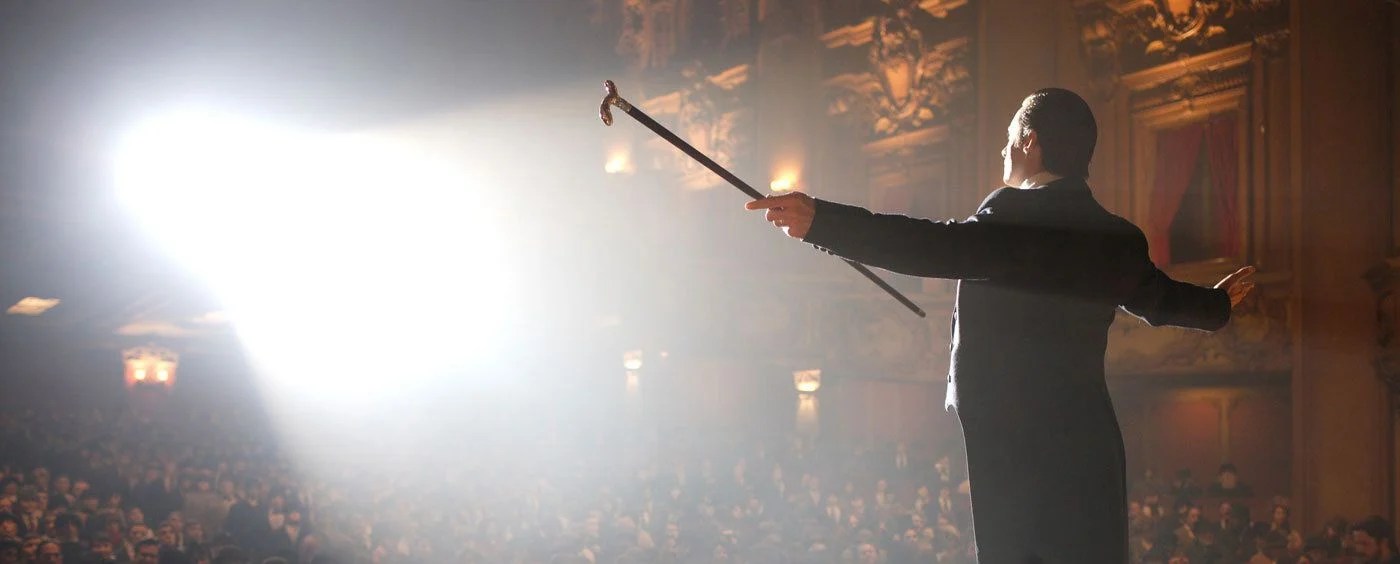 Un homme écarte les bras sur scène dans The Prestige.