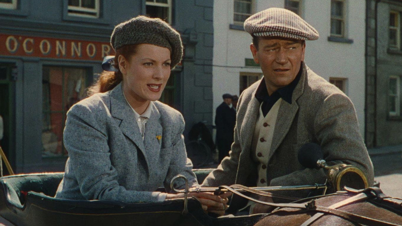 A woman and man sit together dressed in 1920s outfits in The Quiet Man.