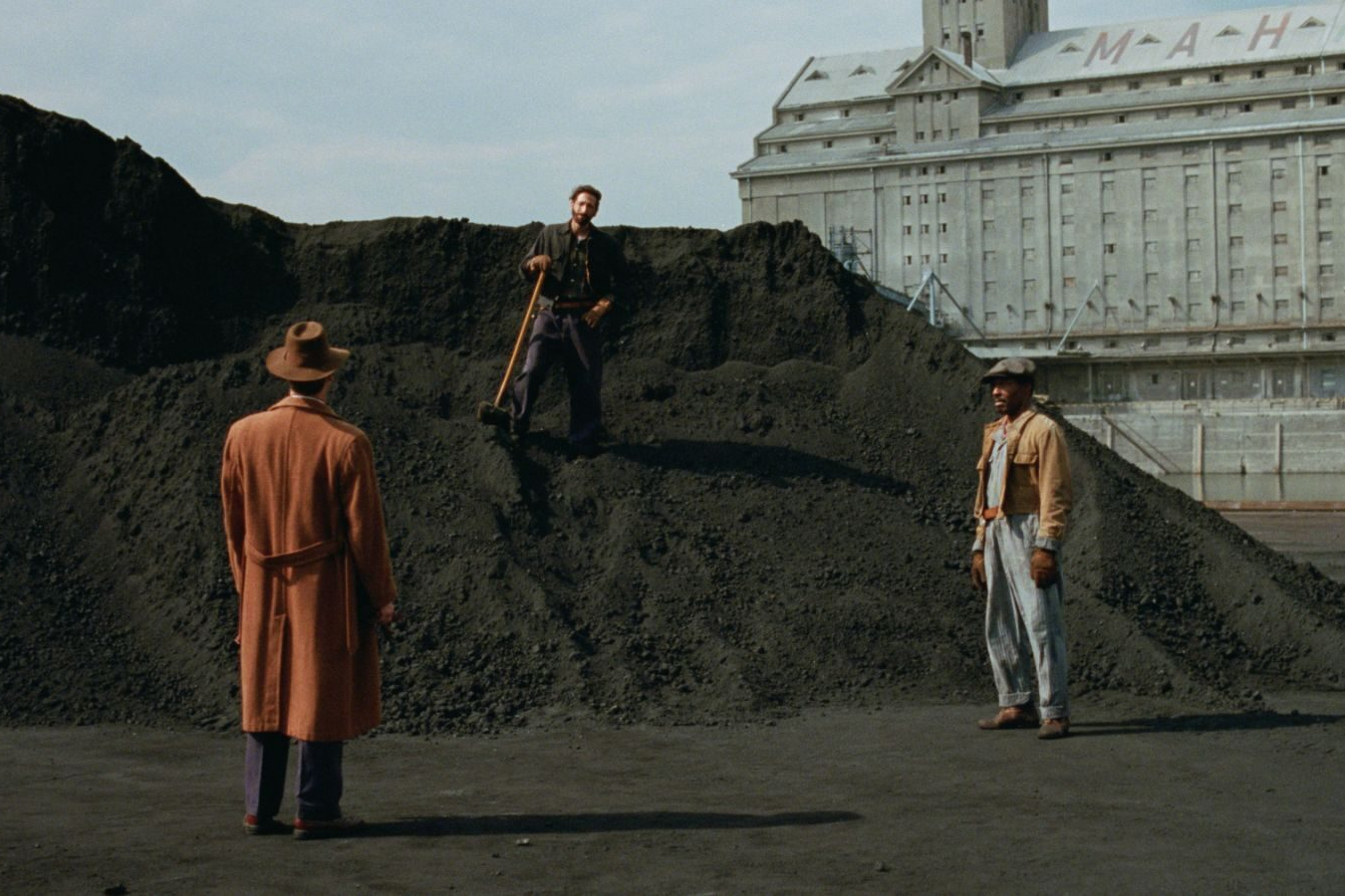 Adrien Brody stands on a pile of dirt in a still from the movie The Brutalist.