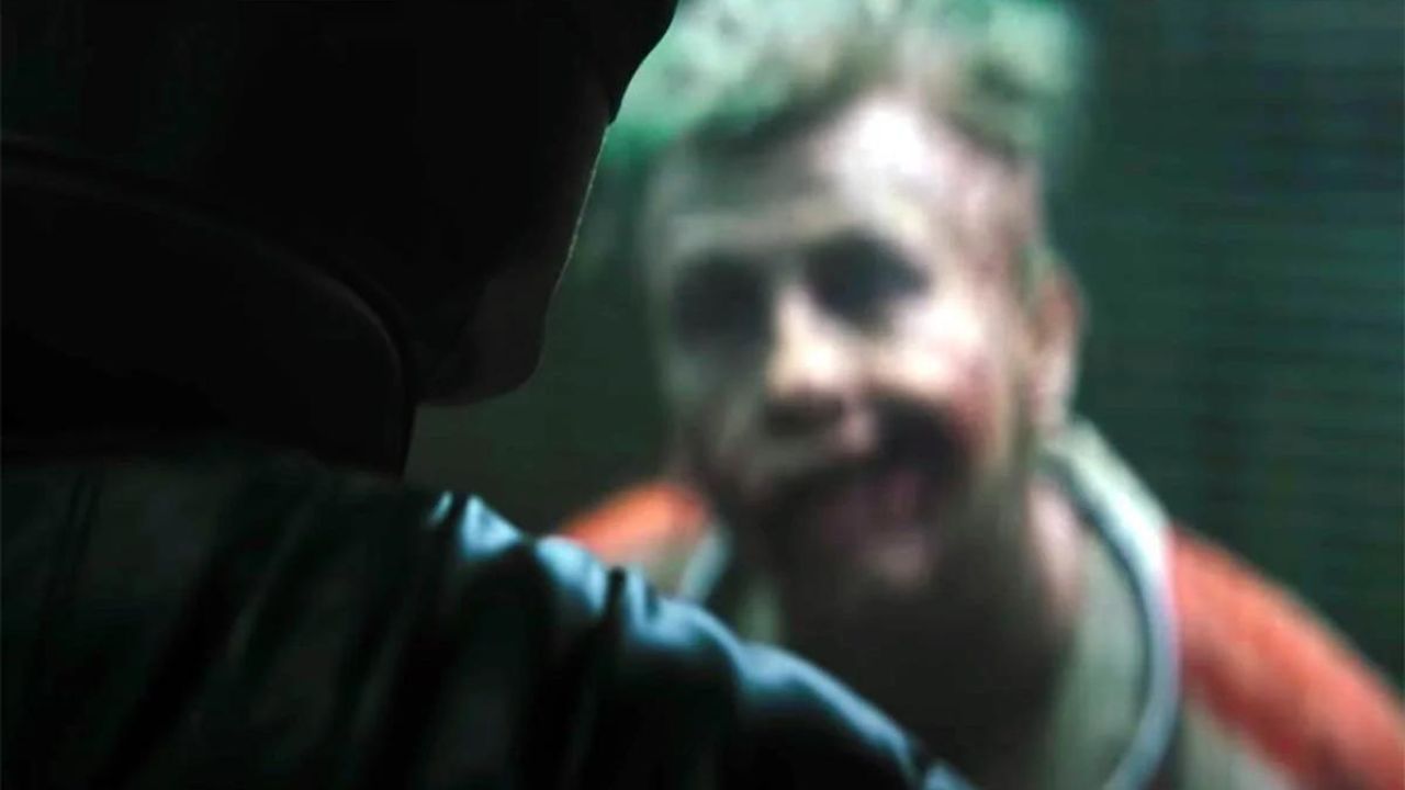 Barry Keoghan como el Joker mirando hacia adelante desde detrás de una vidriera en The Batman.