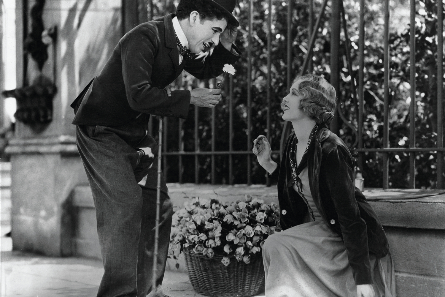 Charlie Chaplin lächelt ein Blumenmädchen in „Lichter der Stadt“ an.