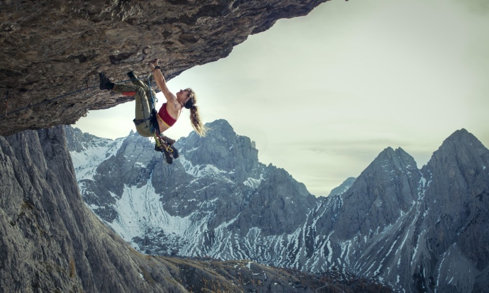 A female hangs disconnected a cliff arsenic she climbs.