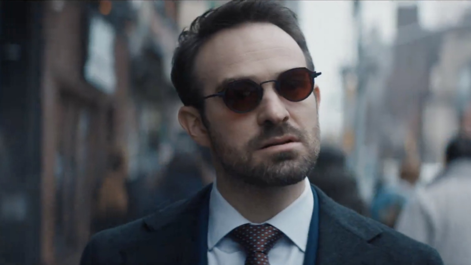 Matt Murdock walks and stares while wearing glasses.