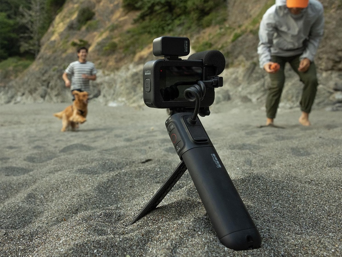 Die GoPro Hero 12 Black Creator Edition auf einem kleinen Stativ am Strand aufgestellt.