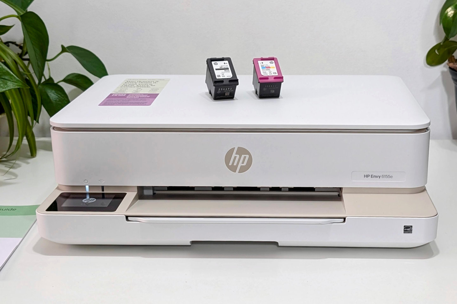 O discreto Envy 6155e da HP fica em um suporte de impressora branco.