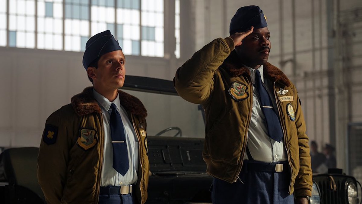 An Air Force member salutes while his comrade stands besides him.