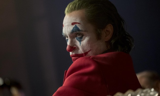 Joaquin Phoenix in clown makeup smirks and looks.