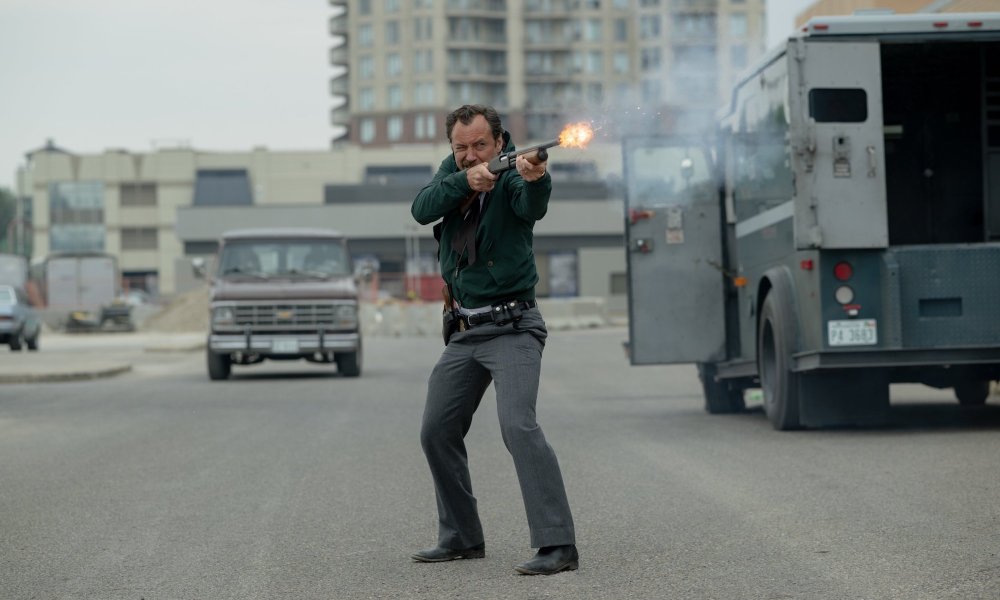 Jude Law fires a gun on the street.