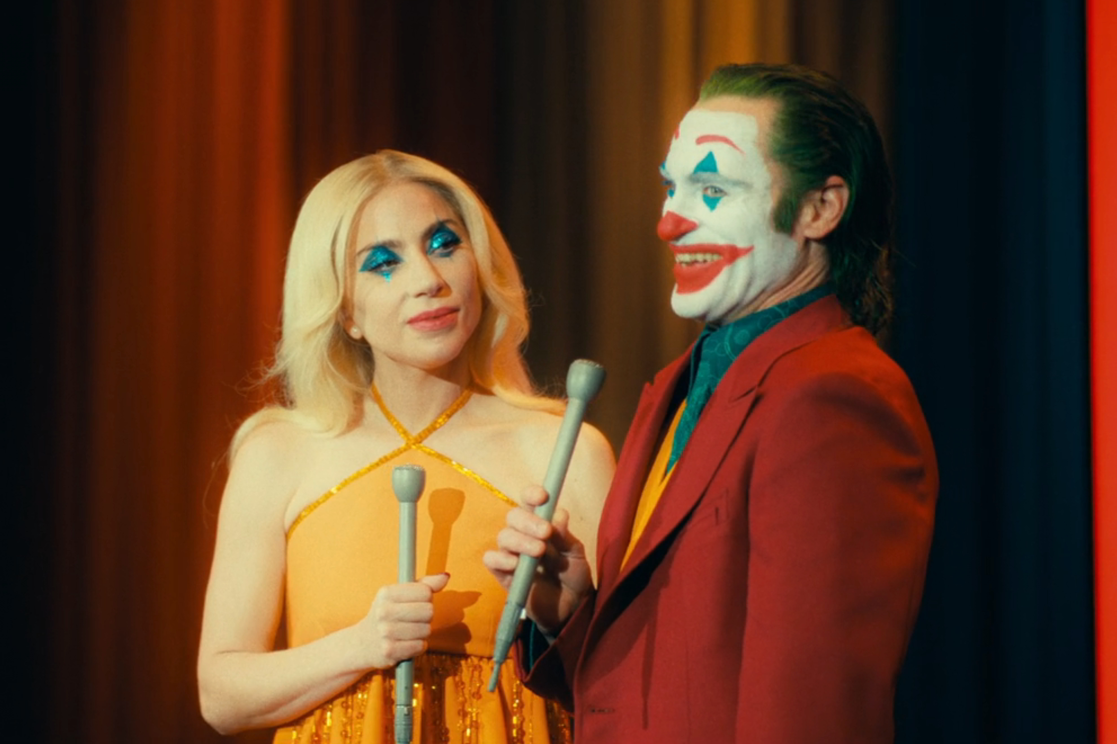 Lady Gaga and Joaquin Phoenix hold microphones in Joker 2.