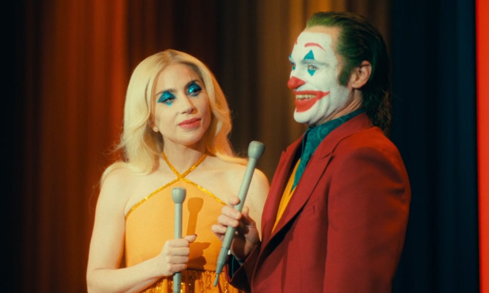 Lady Gaga and Joaquin Phoenix hold microphones in Joker 2.