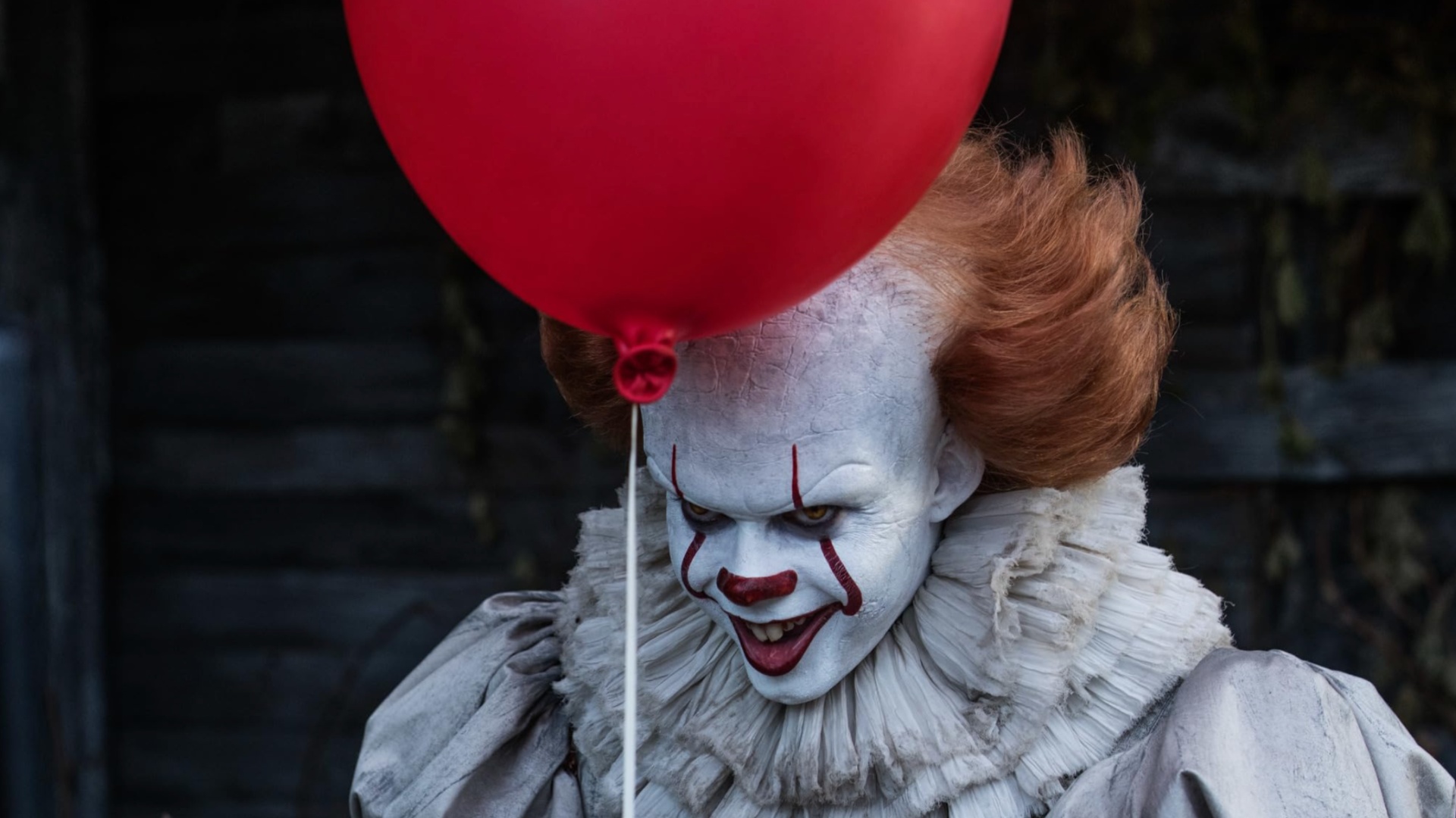 Pennywise the clown holds a red balloon.