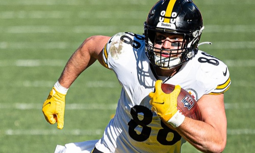 A Pittsburgh football player holds a ball and runs.