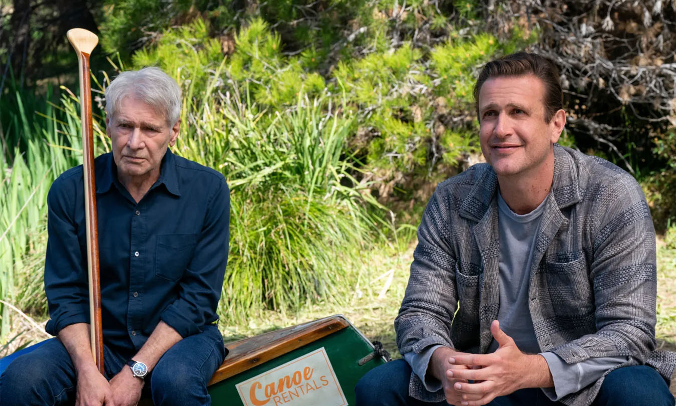 Harrison Ford y Jason Segel sentados uno al lado del otro afuera en una escena de Shrinking.