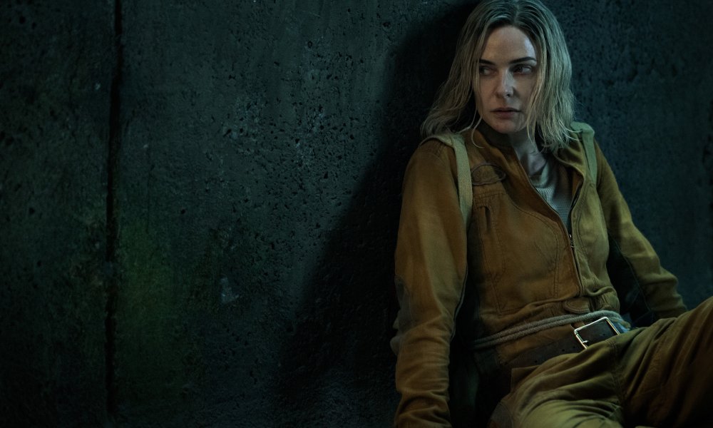 A woman leans against a wall in Silo.