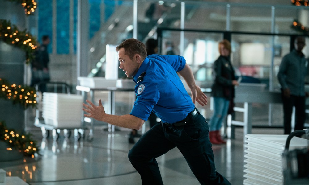 Taron Egerton sprints through an airport.