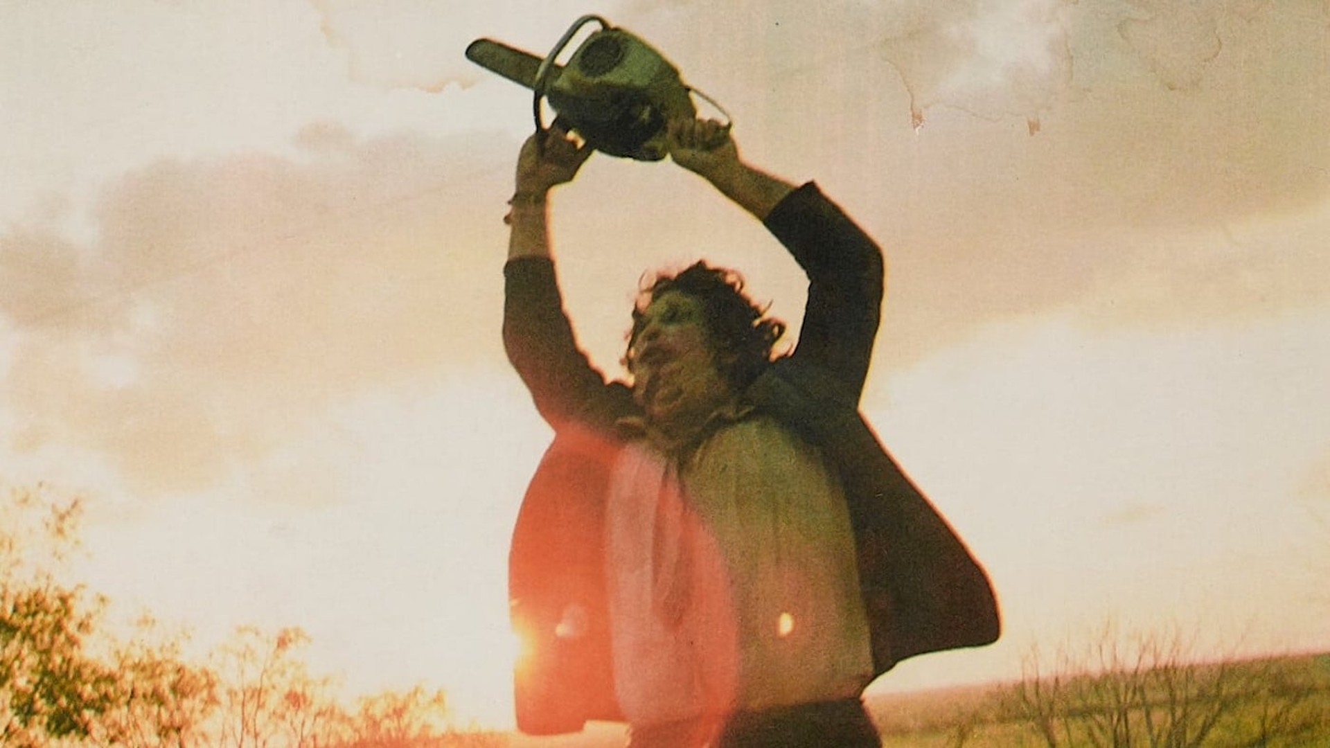 Leatherface lève sa tronçonneuse vers le ciel, un soleil brillant derrière lui, dans une image tirée de l'original The Texas Chain Saw Massacre.