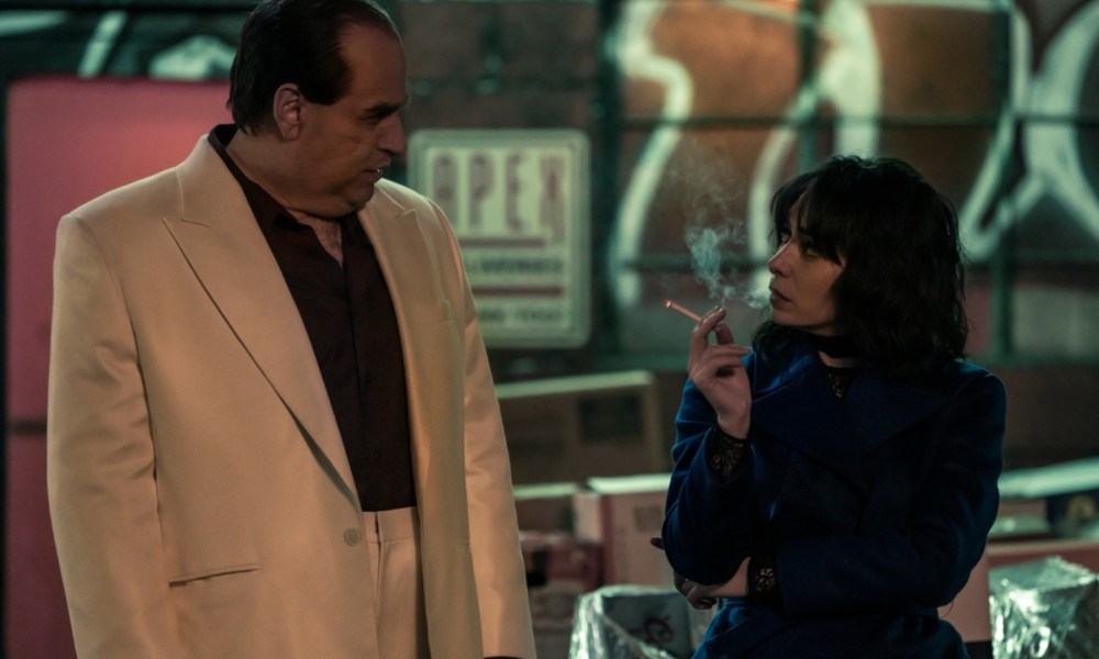 A woman smokes a cigarette as a man stands next to her.