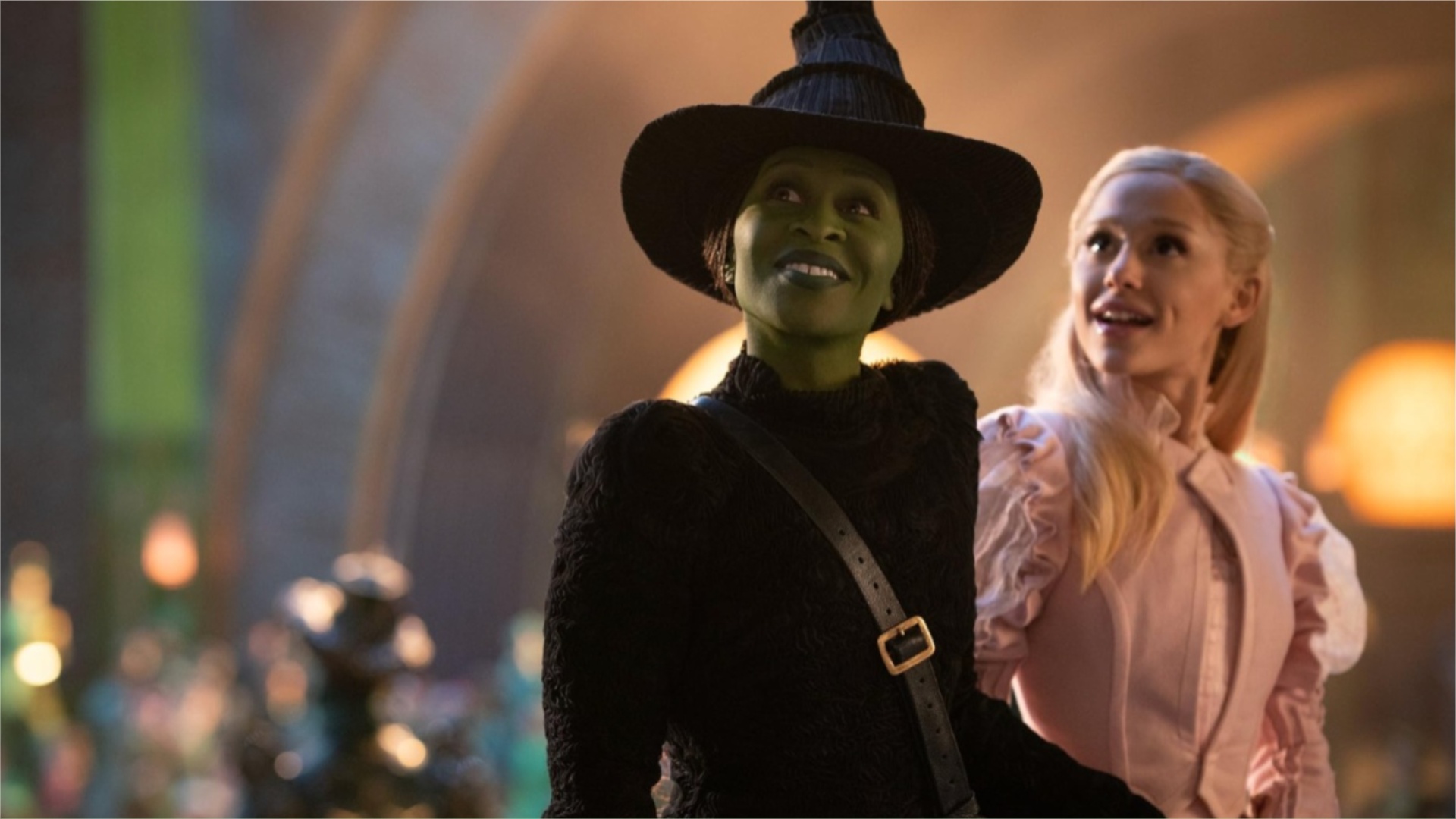 Cynthia Erivo and Ariana Grande smile in a still from the movie Wicked.