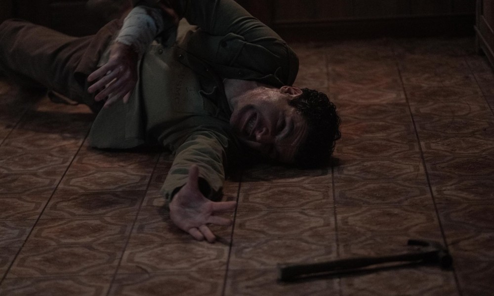 A man on the ground reaches for a weapon.