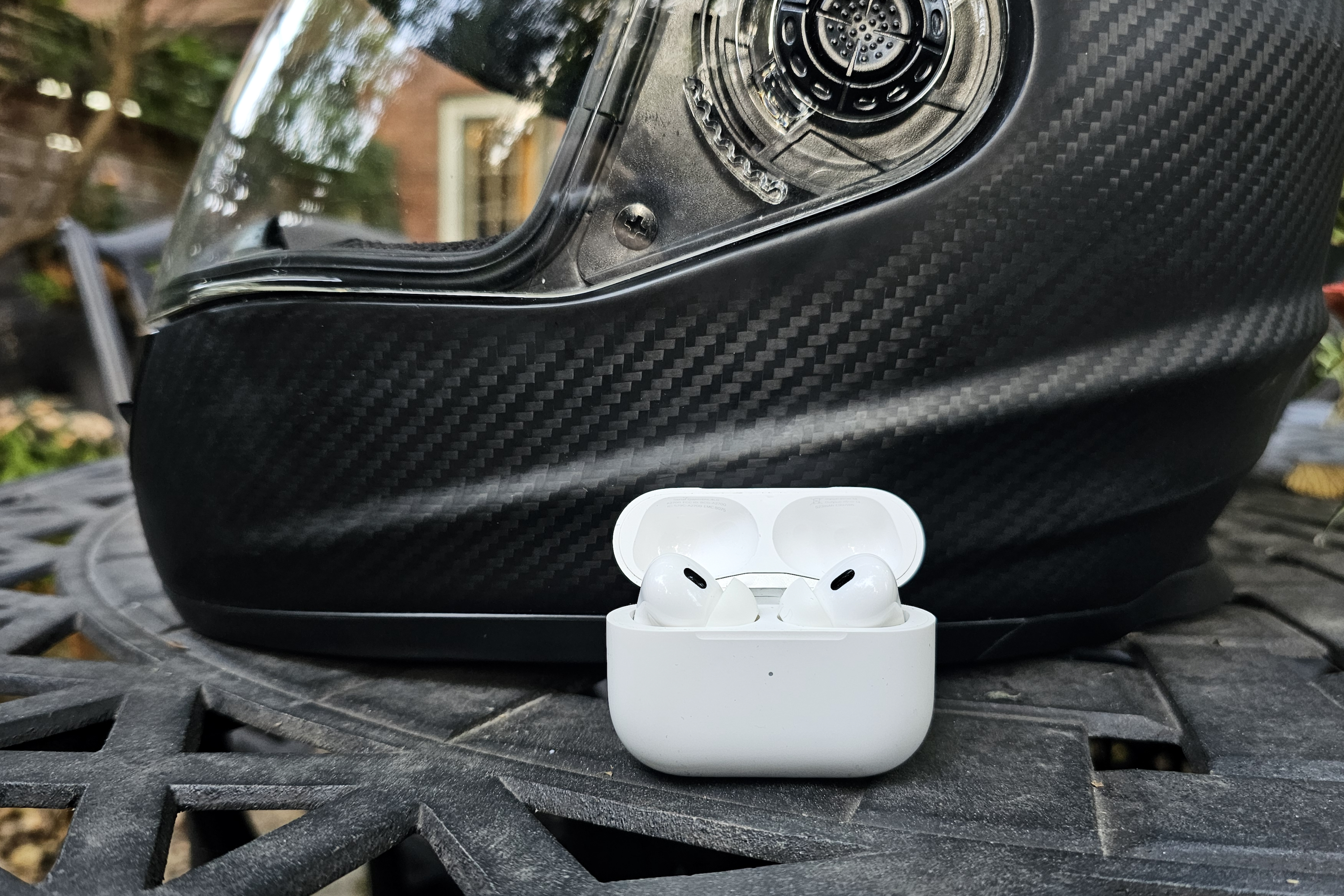 Apple AirPods Pro 2 assis devant un casque de moto.