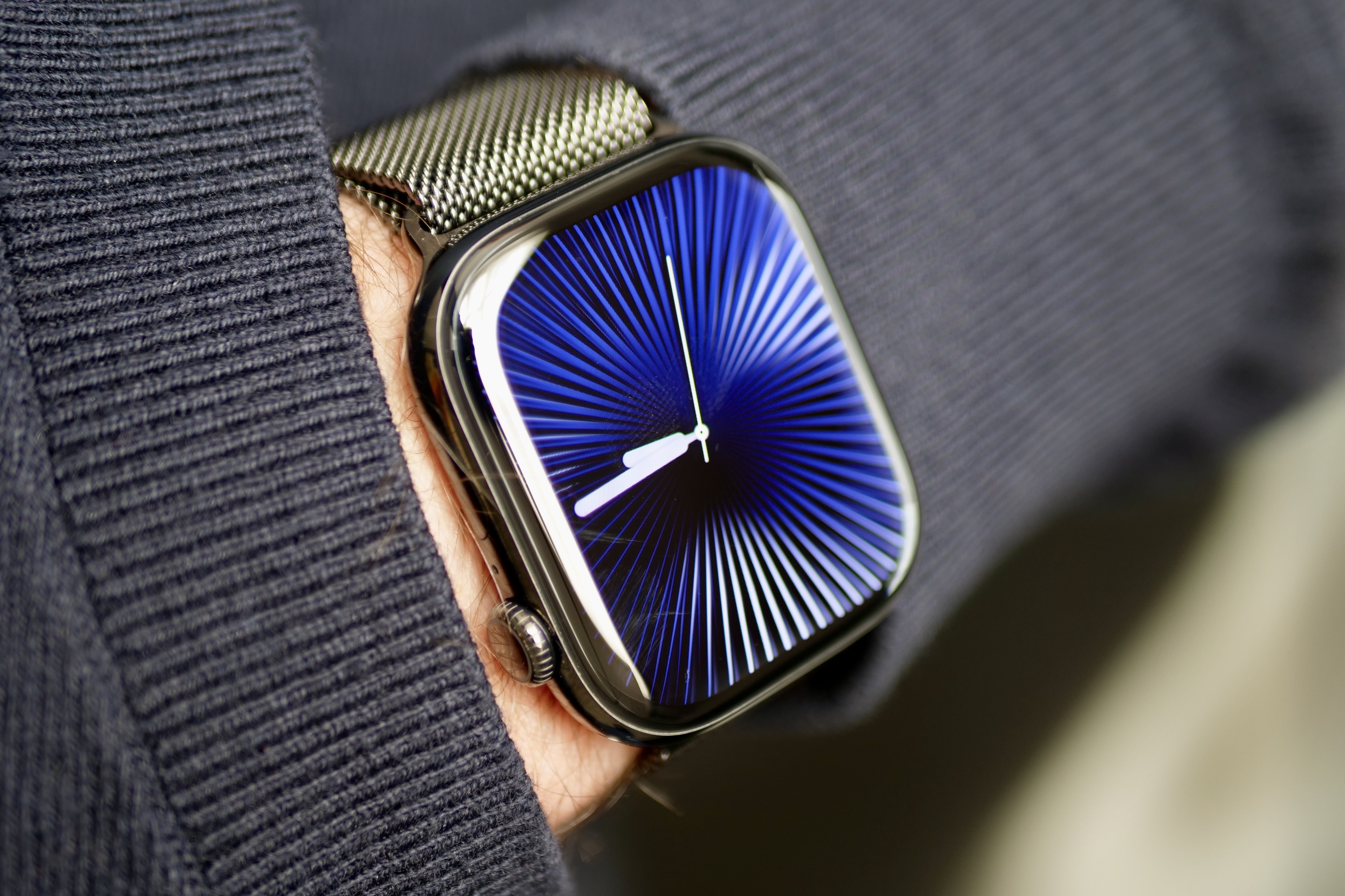 Eine Person, die die Apple Watch Series 10 aus Titan mit dem Reflections-Zifferblatt trägt.