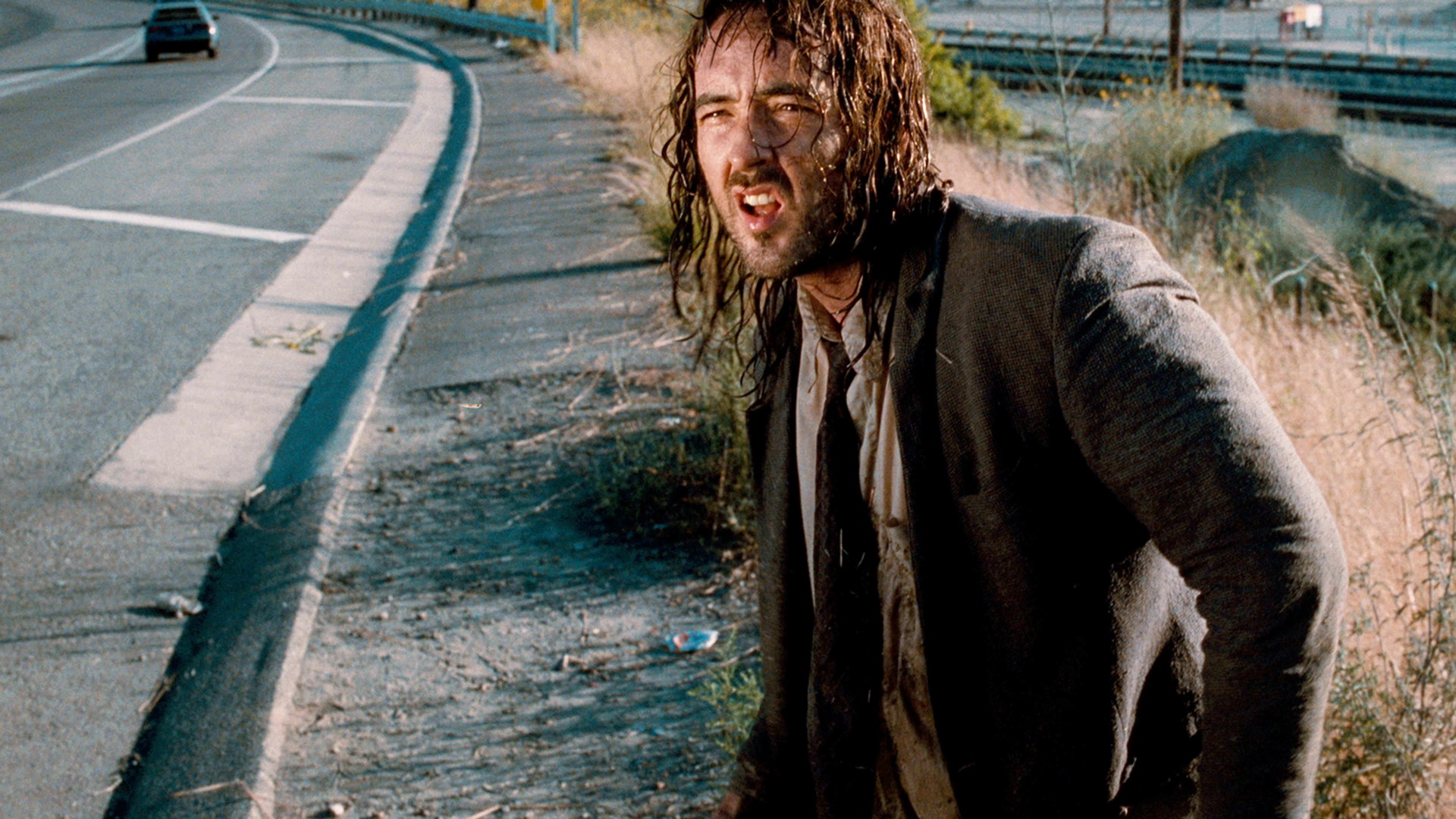 A dirty man stands near a highway in Being John Malkovich.