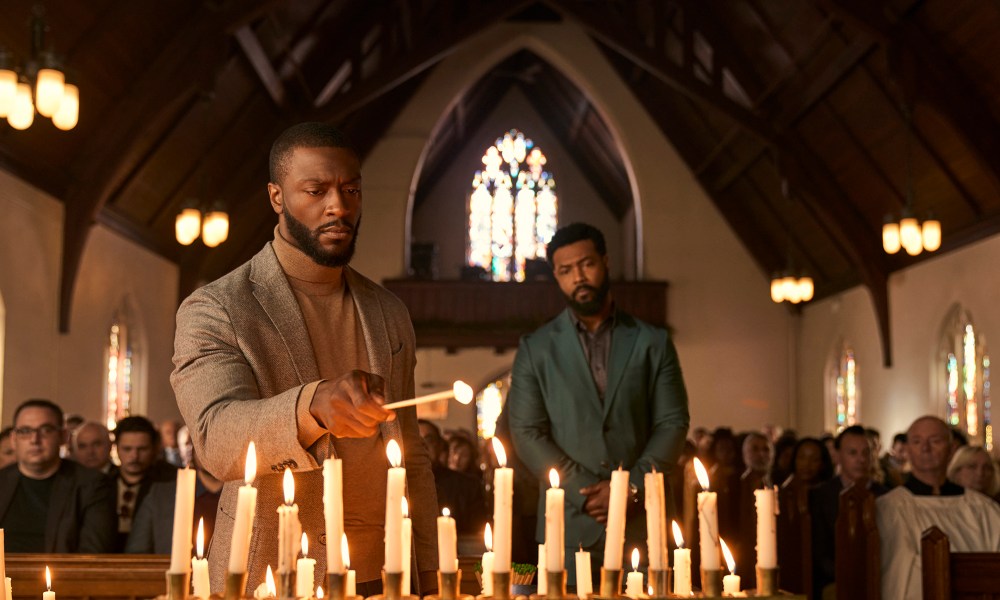 Alex Cross lighting candles in a church as others look on in Cross on Amazon Prime Video.