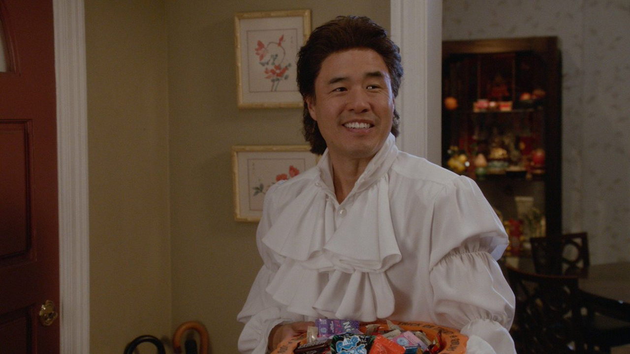 Louis from Fresh Off The Boat dressed like Seinfeld with longer hair and a white puffy shirt.