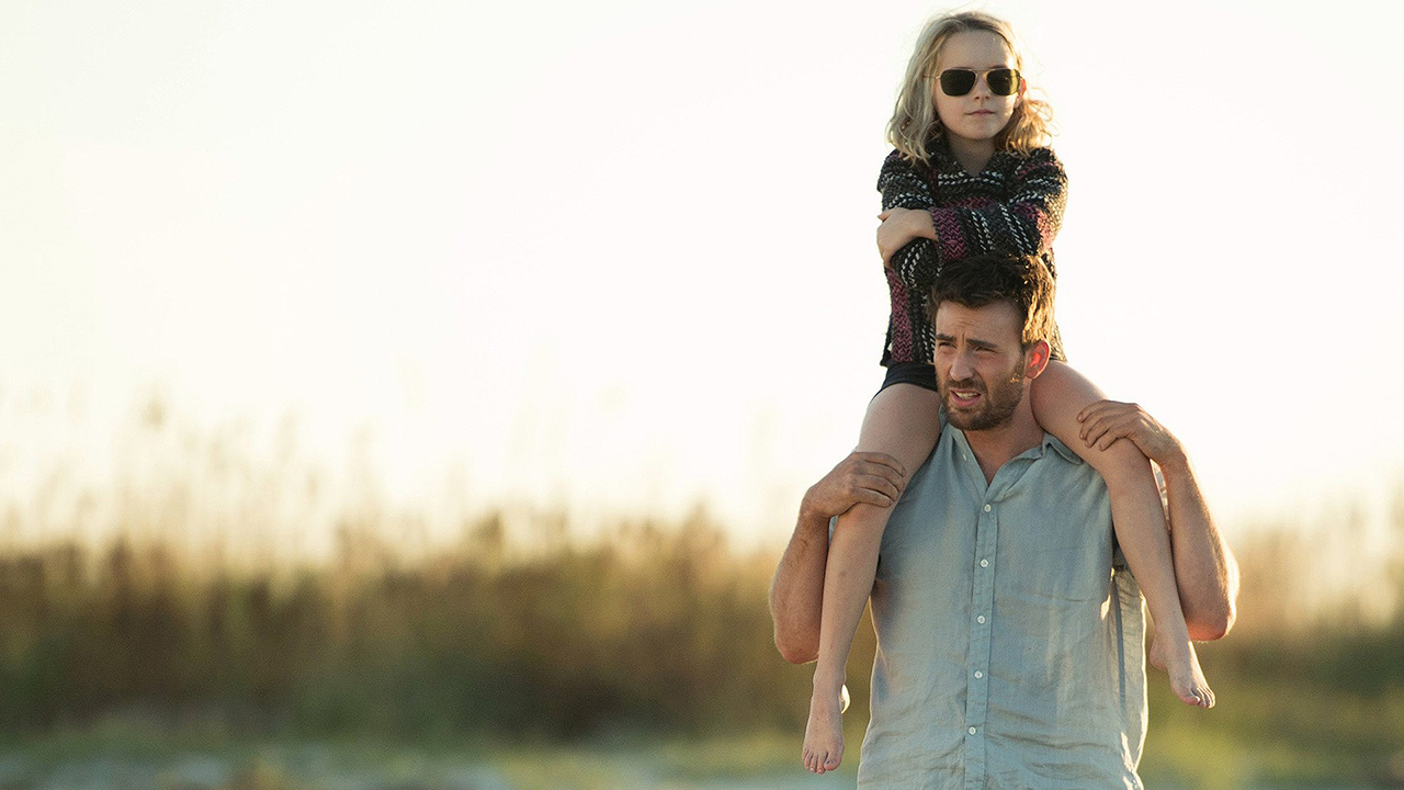 Chris Evans out in a field with a young girl wearing sunglasses over her shoulders in Gifted.