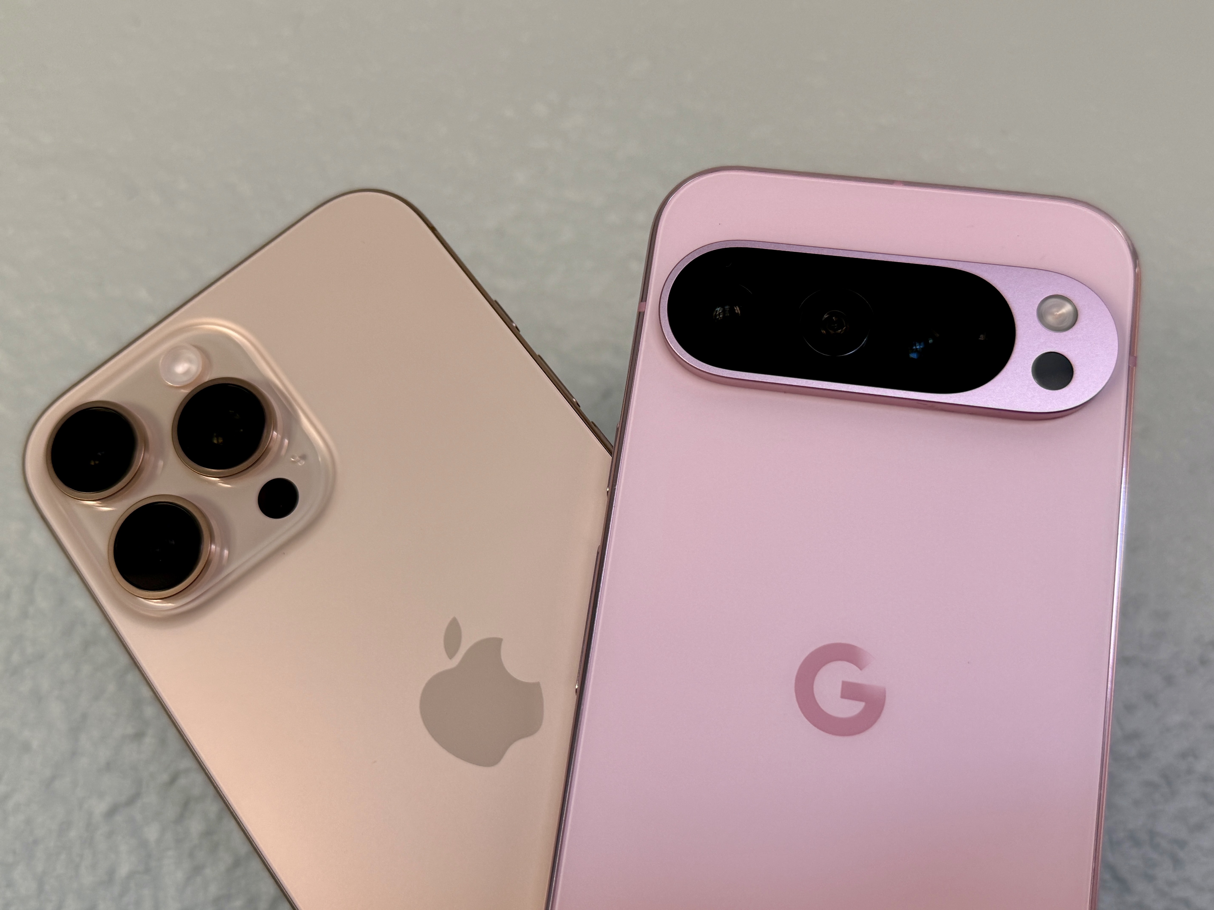 Apple iPhone 16 Pro Max in Desert Titanium (links) und ein Rose Quartz Google Pixel 9 Pro.