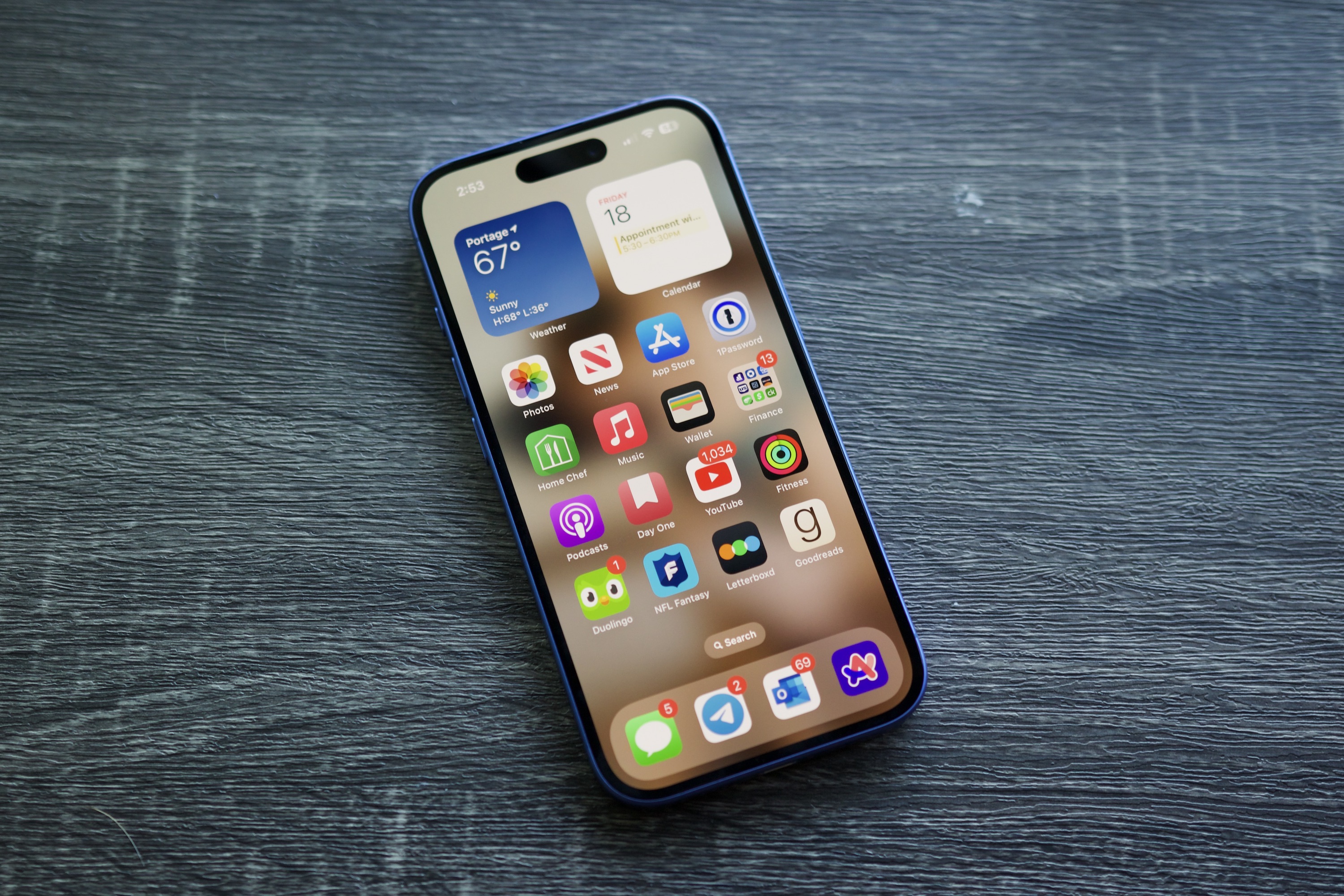 An iPhone 16 laying on a shelf with its screen on.