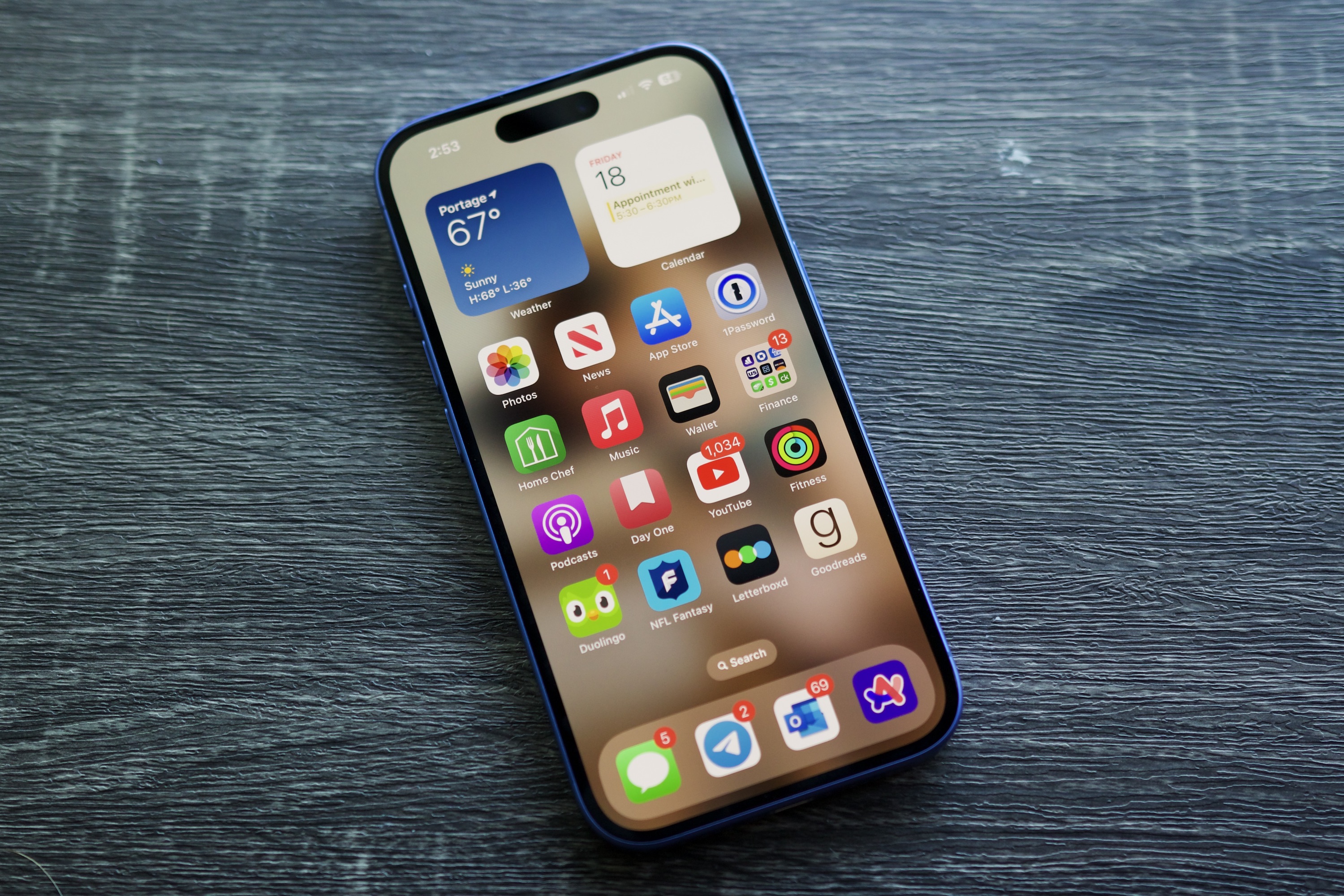 An iPhone 16 laying on a shelf with its screen on.