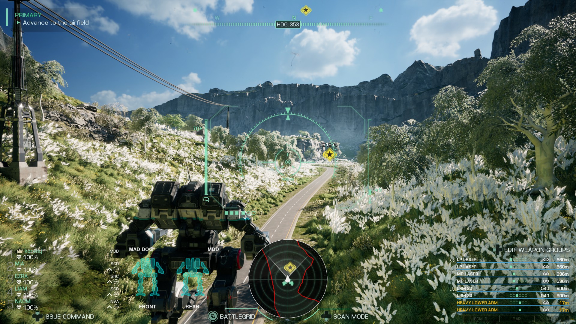 Um mech de tamanho médio viaja ao longo da estrada sob um céu azul cercado por flores em Mechwarrior 5 Clans.