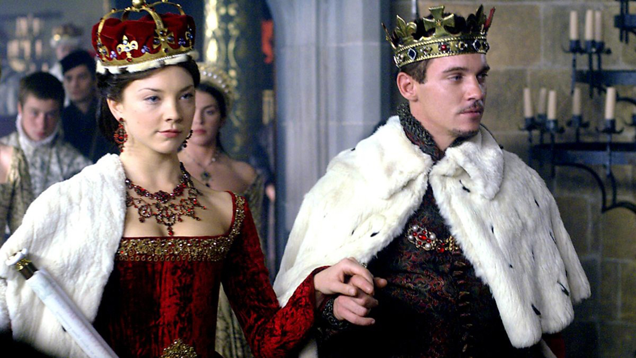 A regal woman and man walk with hands linked in The Tudors.