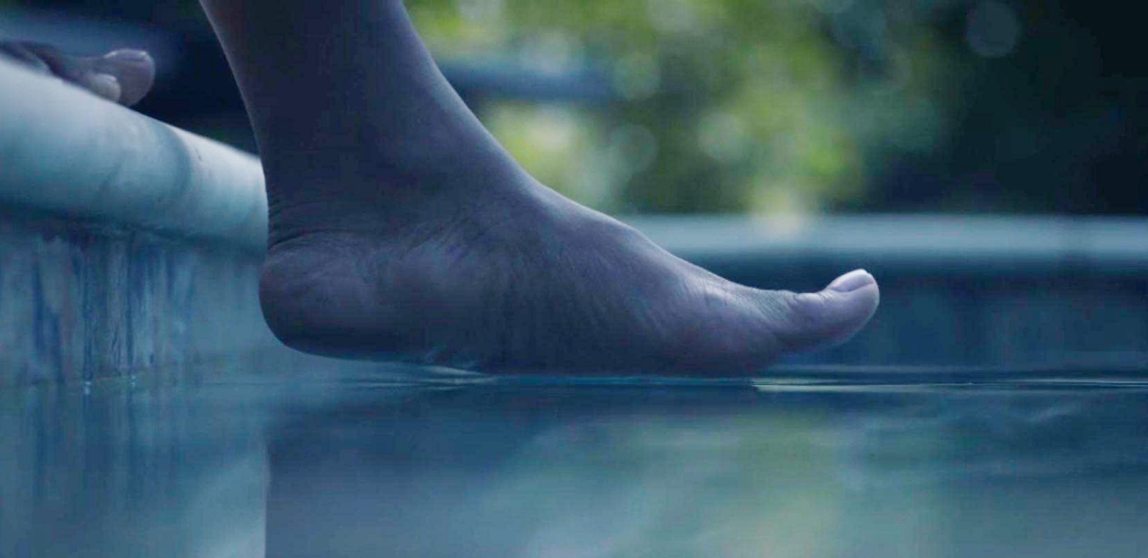 Une femme met son pied dans une piscine dans Watchmen.