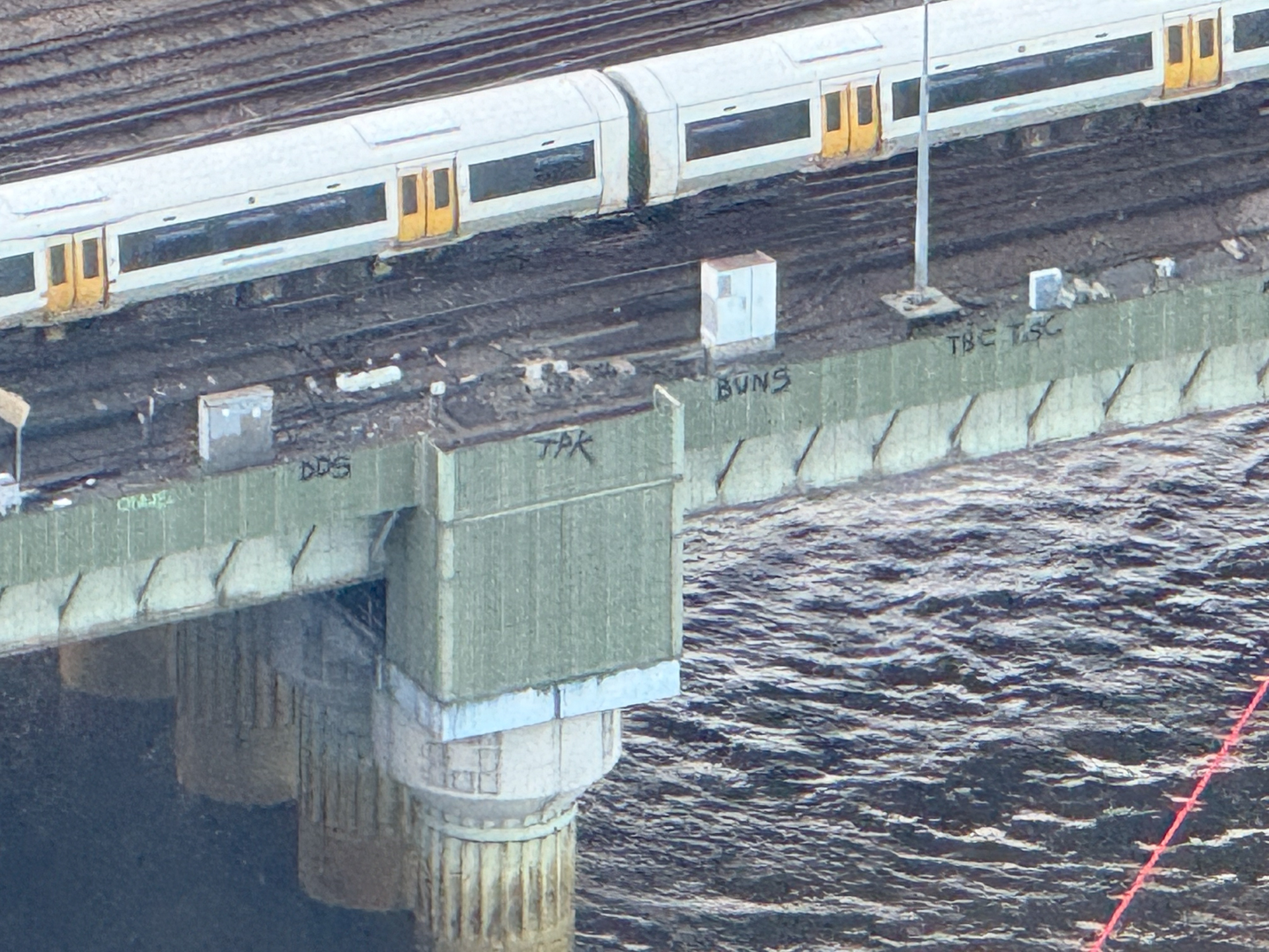 Foto tomada con un zoom de 25x en el iPhone 16 Pro que muestra un grafiti en el costado de un puente en Londres.