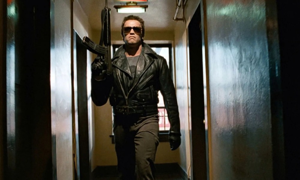 Arnold Schwarzenegger as the Terminator holding a gun while walking down a hallway.