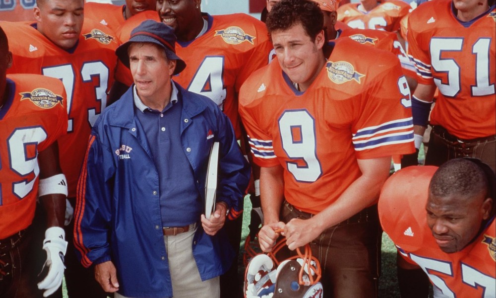 A group of football players stand with their coach.