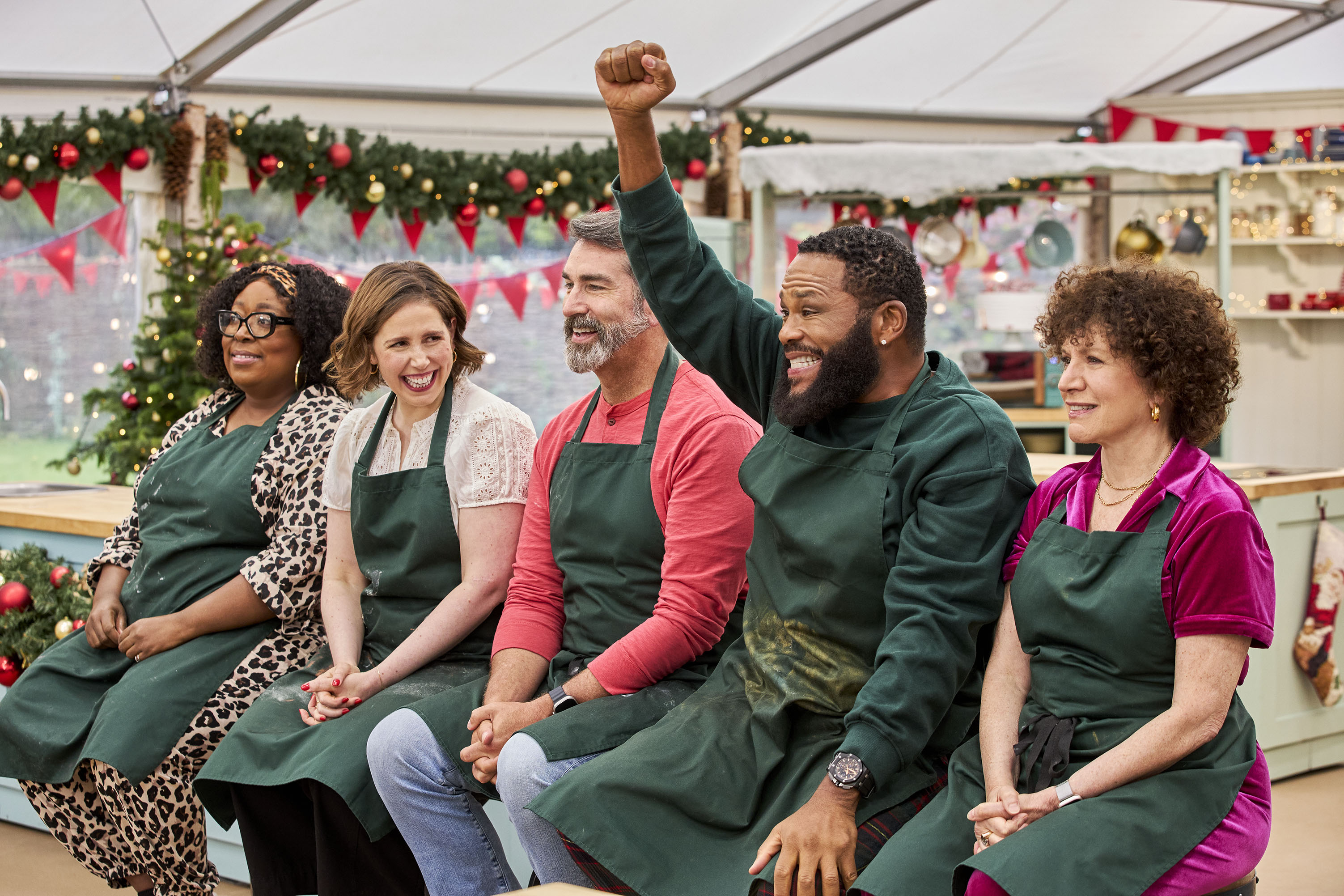 Five people sit down while wearing aprons.