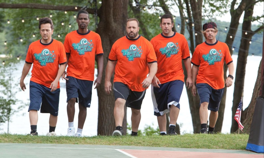 Five men walk up a hill onto a basketball court.