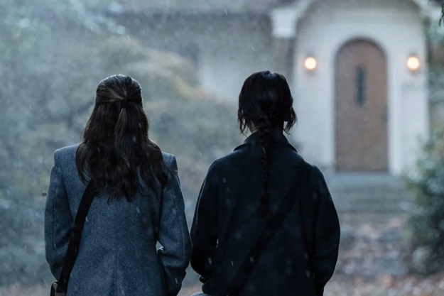 Two girls stand in front of a house in Heretic.