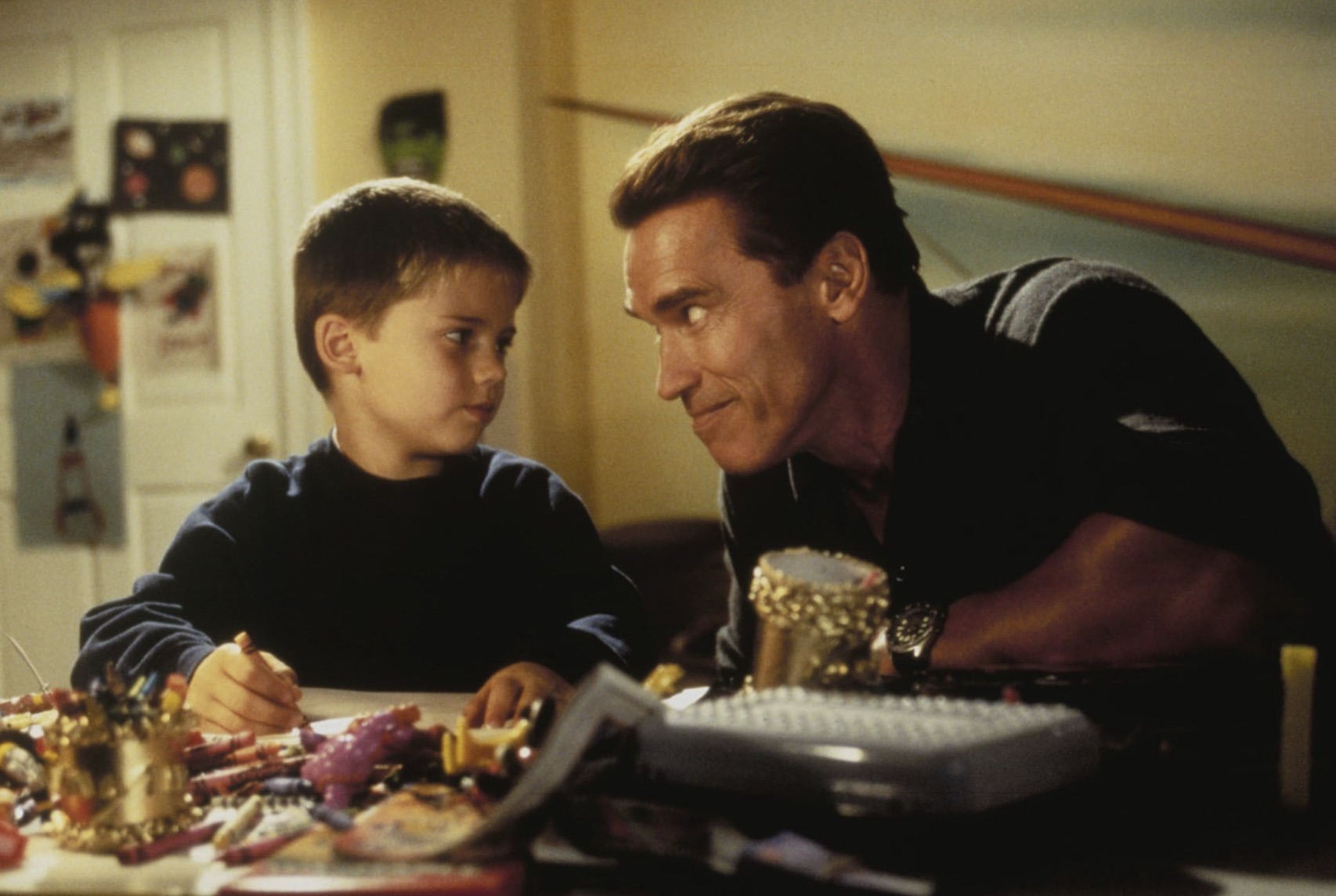 Un homme sourit à son fils assis à une table.