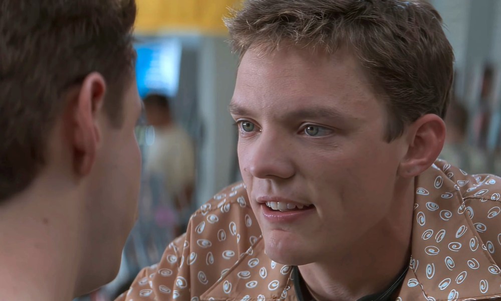 Matthew Lillard smirks in a video store in Scream.